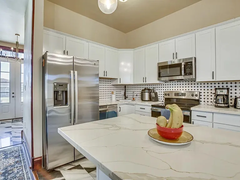 Spacious eat-in kitchen with a large island, ample white cabinetry, and stainless steel appliances for easy meal prep.