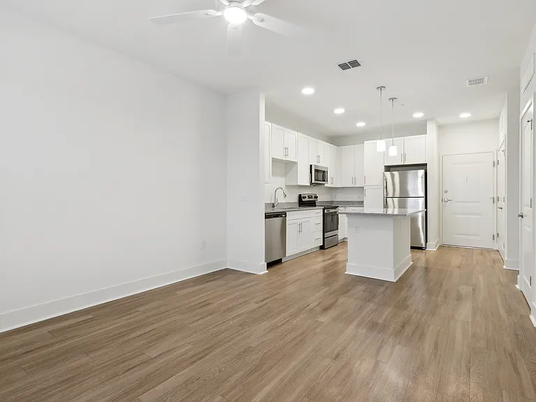 Modern open-concept kitchen with sleek stainless steel appliances, elegant white cabinetry, and warm wood-tone flooring.