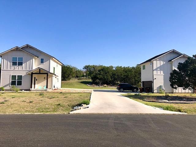 Front view of the two homes. Bluebonnets in the front yard! The rear yard in this photo is extensive and very private with wildflowers, wild grasses and cedar and oak trees.