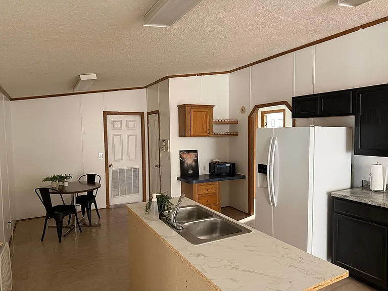 Eat-in kitchen with peninsula sink, ample cabinet storage, and a full-size refrigerator plus a dedicated dining nook.