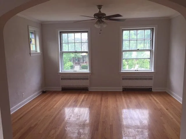 huge living room with ceiling fan, stained glass, crown molding, and refinished hardwoods