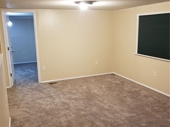 Living room to the left of the front door with the door leading into the master bedroom suite.