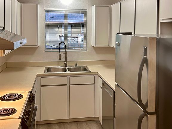 Kitchen with new vinyl flooring and new stainless steel fridge, dishwasher and range hood.