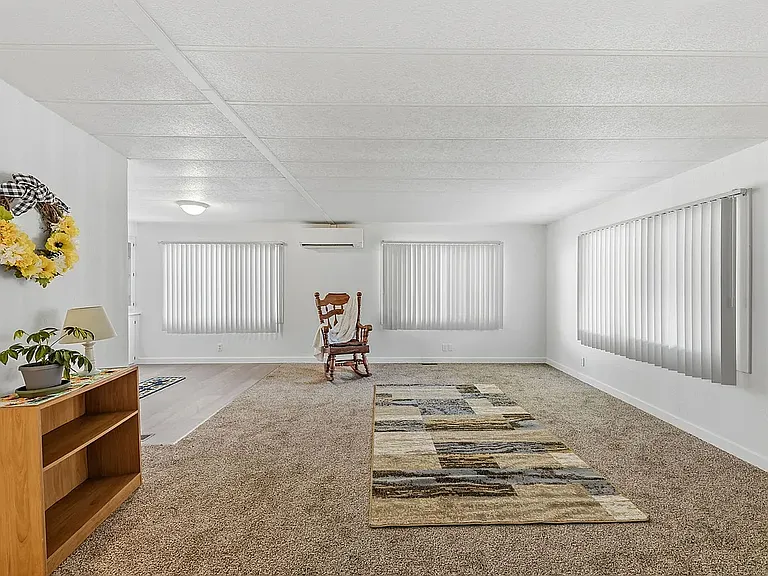 Living room as seen from entry. New carpet. Lots if indirect light. Mini split cooling on wall between windows. Freshly painted. Giving that homey feeling