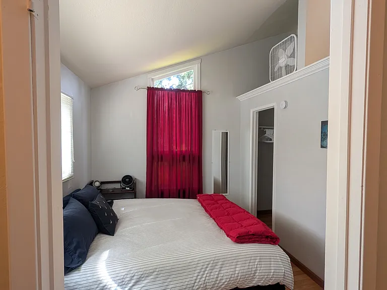 Peaceful private bedroom with Queen bed with view of quiet neighborhood setting and fenced front yard with greenery