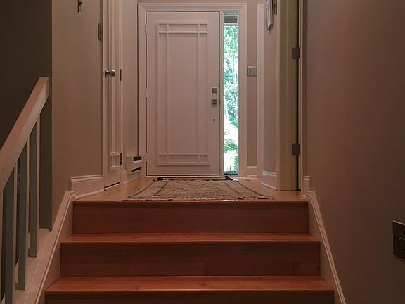 View from living room up to wide entry hallway to custom entry door, half-bath (right door) and garage (left door)