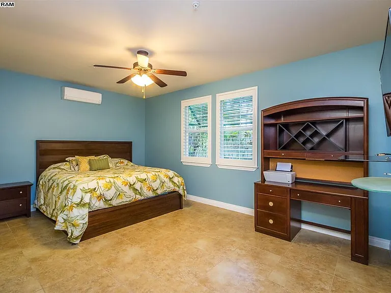 Master bedroom with 2 nightstands, lamps, desk, TV, plantation shutters.