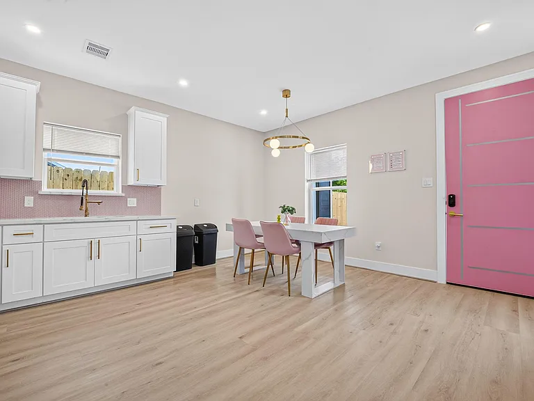 Open kitchen/dining area with ample cabinetry, long counters, and a dedicated table space near large windows.
