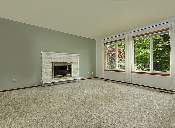 A large light filled living room with a wood burning fireplace.