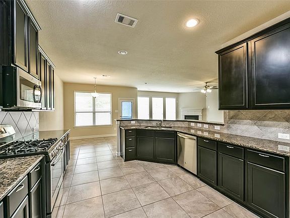 Island kitchen features gas range and stainless steel appliances.