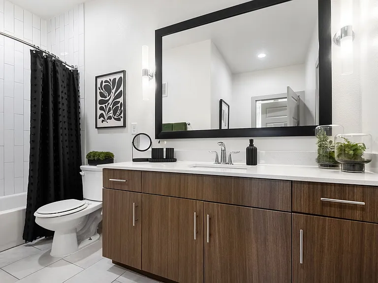 Updated Bathroom Featuring Wide Mirror, Tub, and Chrome Fixtures