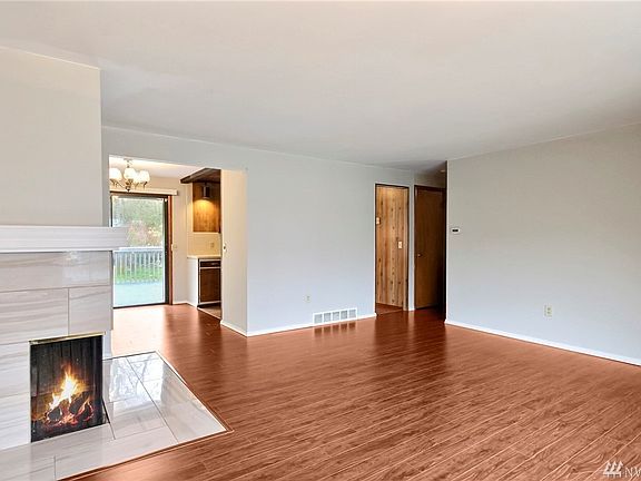 Spacious upstairs living area with a wrapped fireplace and upgraded flooring. 