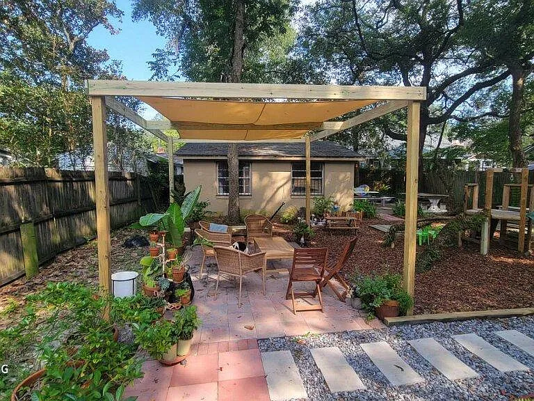 Backyard pergola (fence has been replaced since photo). Oversized 2+ car garage in background.