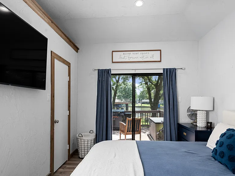 Primary bedroom with king size bed with TV and glass sliding doors to outside patio area.