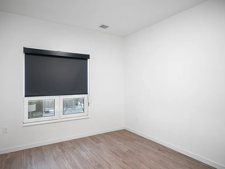 Bright empty room with modern wood flooring, sleek dark window shades, and crisp white walls. Bright empty room with modern wood flooring, sleek dark window shades, and crisp white walls.