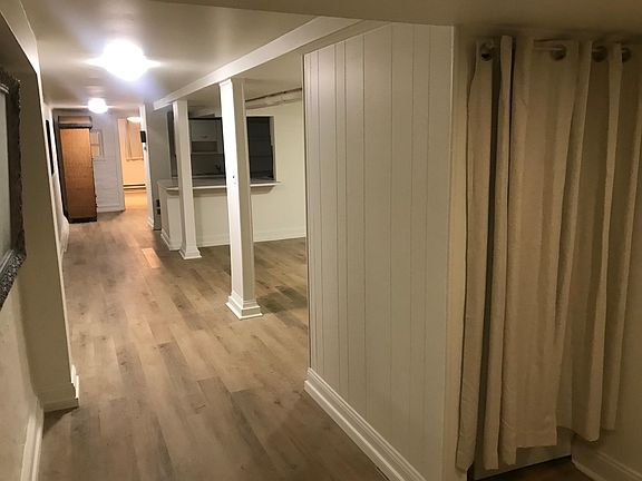 View from entrance hallway toward living room and bedroom. Small stacked washer-dryer behind curtain on right.