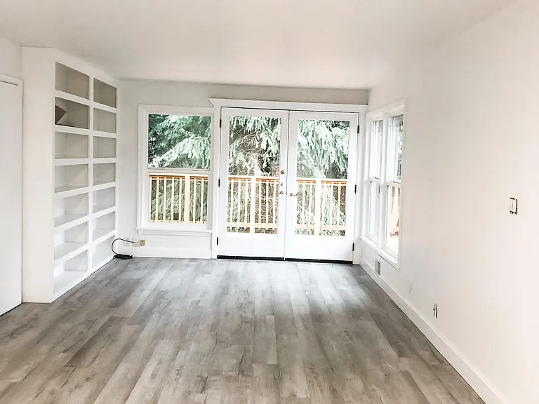 Family room with built in book cases and double french doors onto deck. Plenty of room for a couch and TV. Light and bright with windows along the back of house to let in all the natural light.