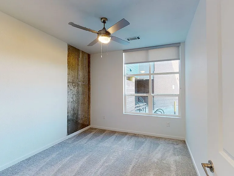 Spacious apartment bedroom with plush carpet flooring.