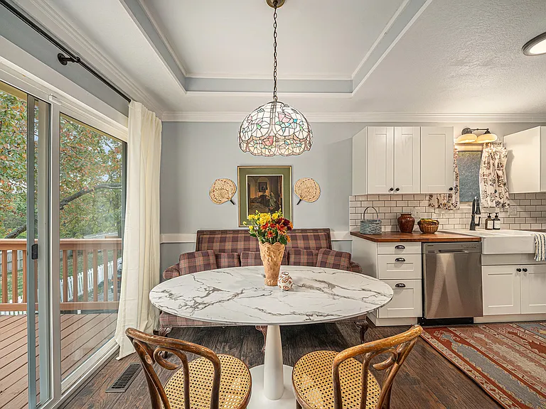 Savor quiet dining moments in this charming nook with 2 chairs and a cozy sofa for two, accented by a vibrant mosaic glass chandelier that brings a unique touch.