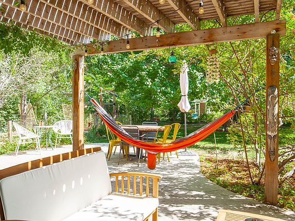 Back patio with pergola, hammock, fireplace, grill, and dining table