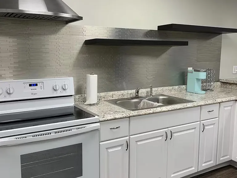 Updated kitchen with granite-look counters, stainless range hood, double-basin sink, and ample cabinet storage.