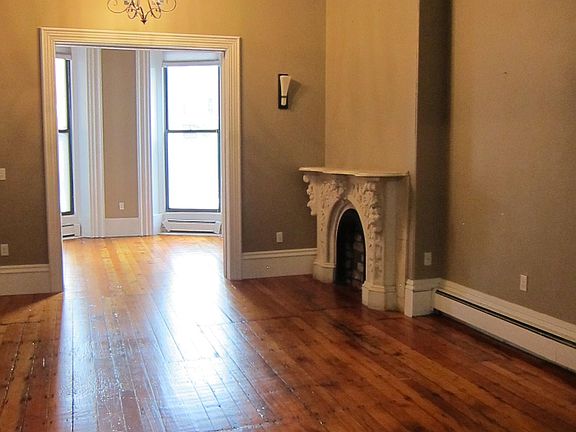 Living room with ornamental fireplace, crown molding, hardwood floors, and extra large windows