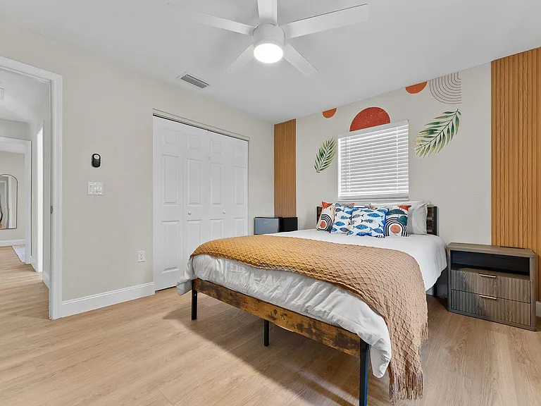 Furnished bedroom with a ceiling fan, window blinds, double-door closet, and a nightstand for convenient storage.