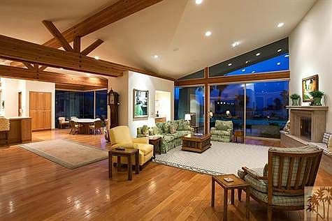Oversized great room with walls of glass and large wood beams.