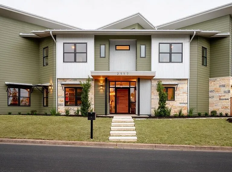 This stunning contemporary home showcases exceptional curb appeal with a durable metal roof, striking architectural lines, and a sophisticated blend of stone, siding, and modern design elements.