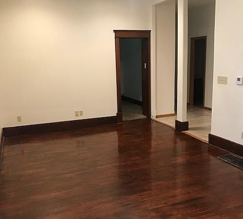 Living room with hardwood floor. The door is to one of the bedrooms.