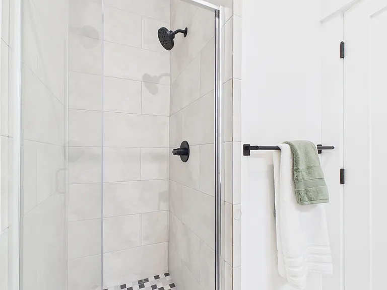 Walk-in tiled shower with glass enclosure, rainfall-style showerhead, and towel bar for everyday convenience.