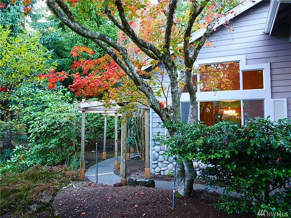 A charming pergola covered path leads the way around the side of the house. You'll love that there is a paved path around the entire house so no muddy toes when enjoying these gardens.