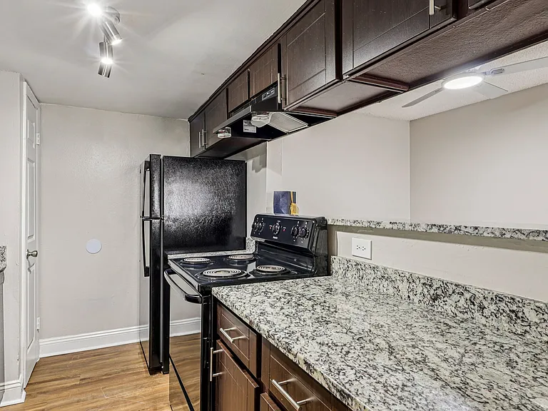 Functional kitchen with granite counters and breakfast bar opening.