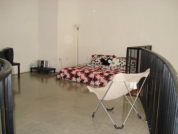 huge bedroom with polished cement floor that overlooks the living area