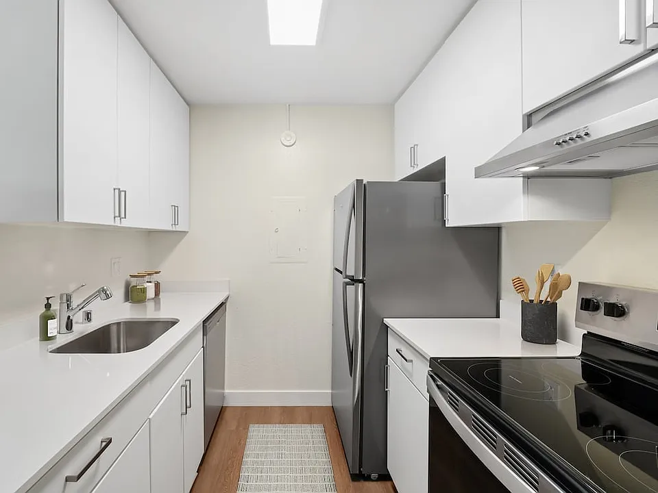 Renovated Package I with white cabinetry, white quartz countertops, stainless steel appliances, and hard surface flooring