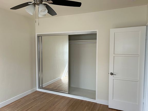 Example photo of mirrored closet doors, ceiling fan in bedroom