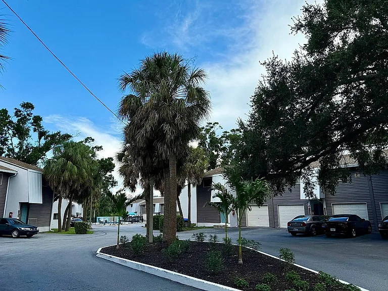 Beautiful apartment complex surrounded by lush palm trees and well-maintained landscaping, offering a serene and inviting atmosphere.