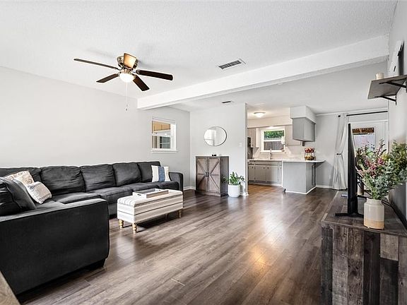 Living room featuring ceiling fan, dark hardwood / wood-style flooring, and beamed ceiling