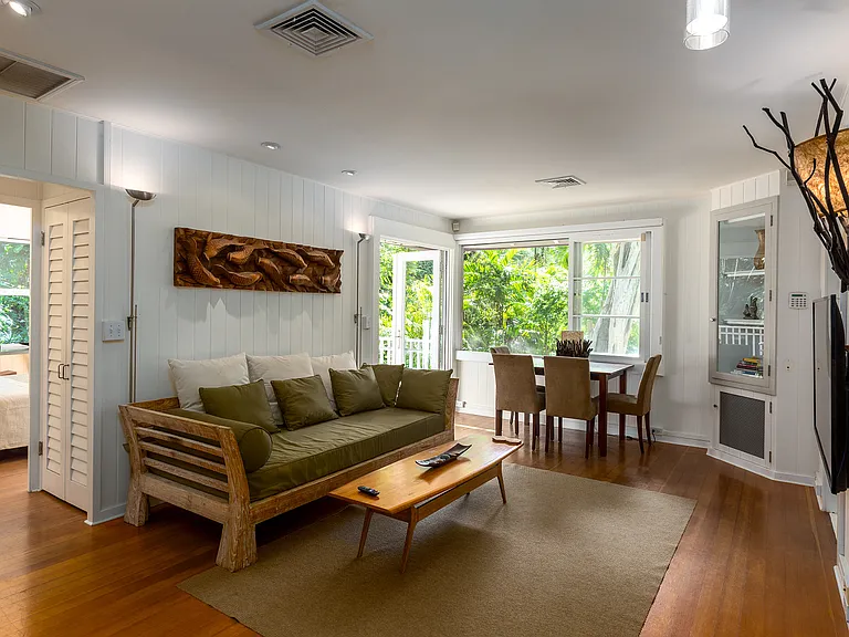 Fully furnished living room with large windows open to view of the greenery