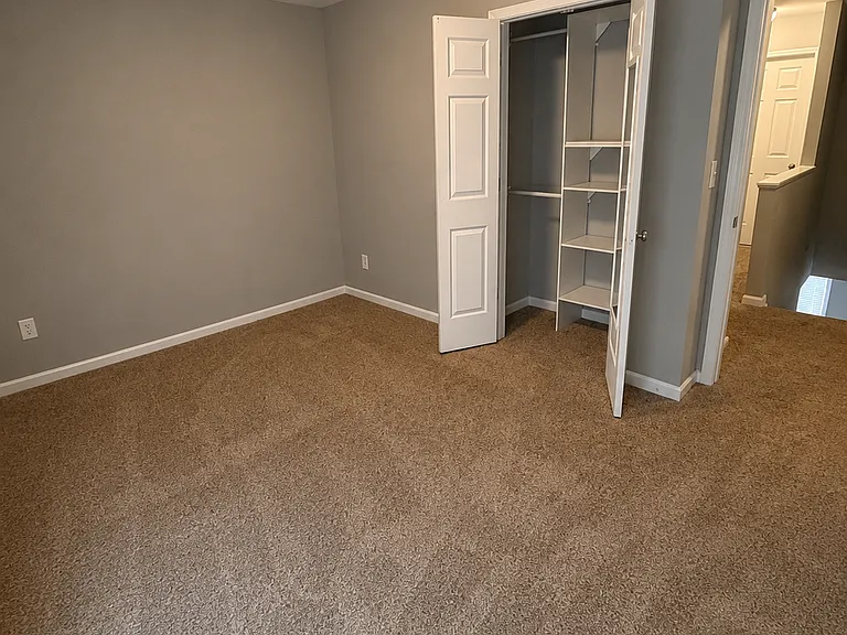 Comfortable secondary bedroom featuring plush carpeting, neutral finishes, and a large window that fills the room with natural light.