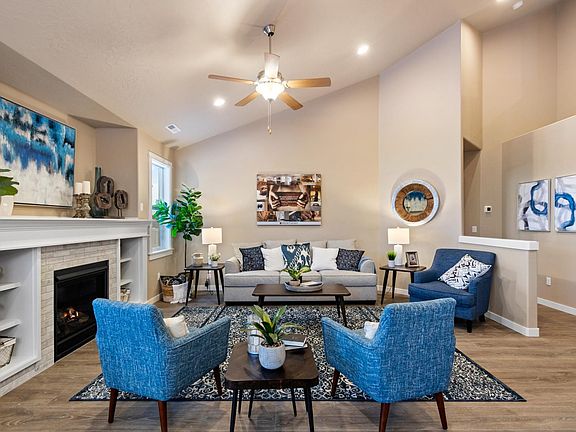 Expansive living room featuring soaring vaulted ceilings, a cozy gas fireplace, and abundant natural light.