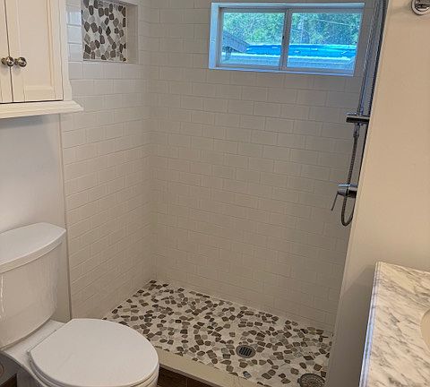 Spacious shower with floor to ceiling decorative tile with chrome shower and wand.