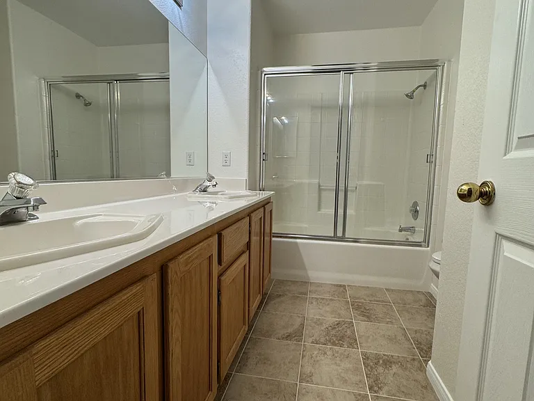 A well-maintained bathroom with a sleek glass-enclosed shower and practical vanity storage.