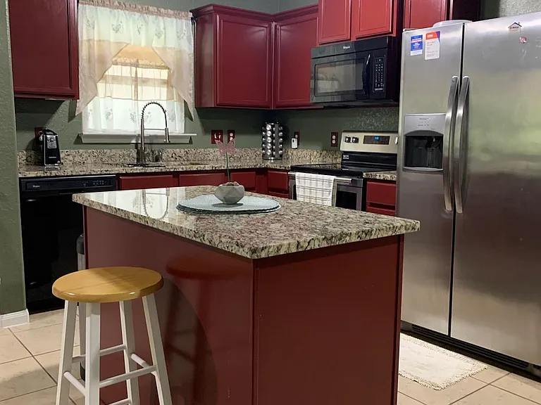 Kitchen with granite island, cherry-tone cabinets, stainless appliances, and a window over the sink for everyday prep.
