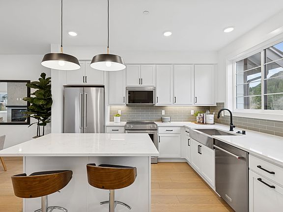 A modern, bright, and spacious kitchen with white cabinets, stainless steel appliances, a large isla