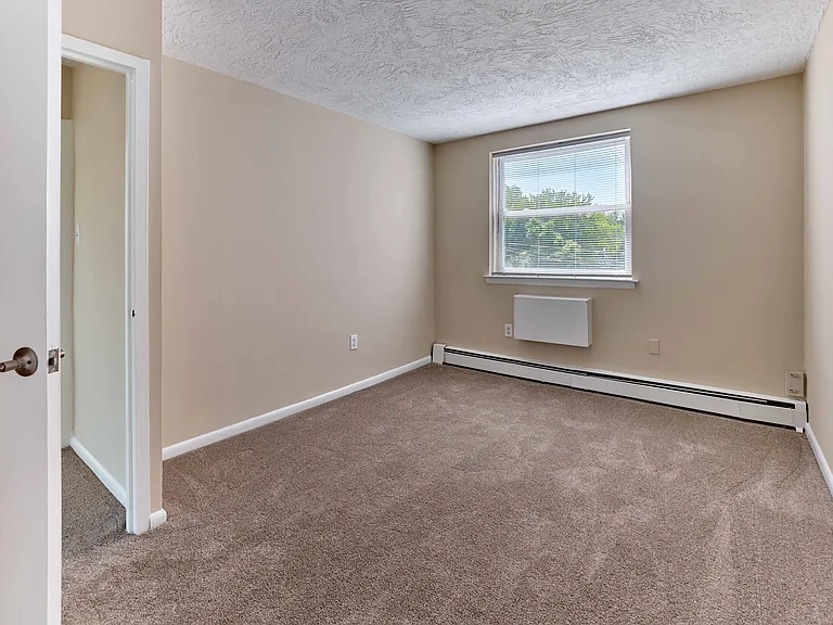 Bright and comfortable carpeted bedroom at Audubon Arms Apartments.