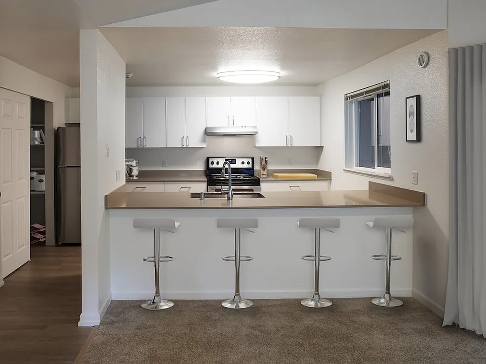 Renovated Package I kitchen with stainless steel appliances, white cabinetry, and grey quartz countertops