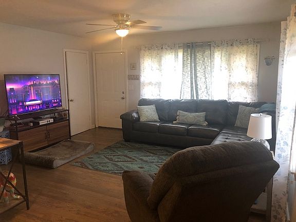 Spacious living room with newly refinished hardwood floors, new ceiling fan, new paint throughout.