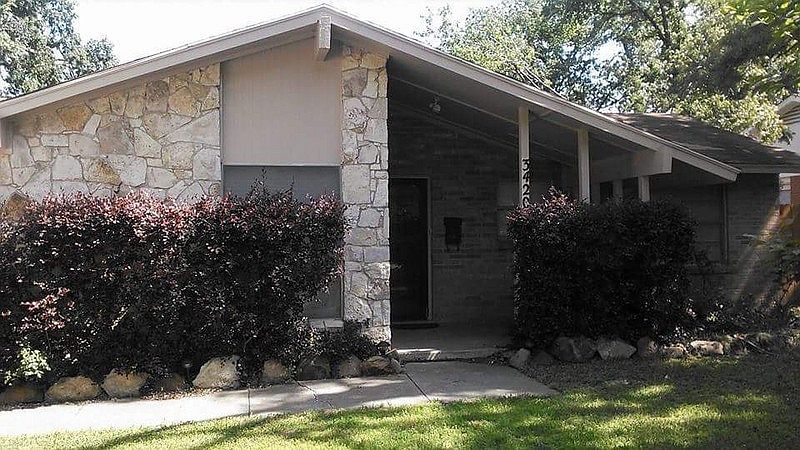 Front view w/covered porch : Brick and stone exterior with an enclosed porch area and landscaping.