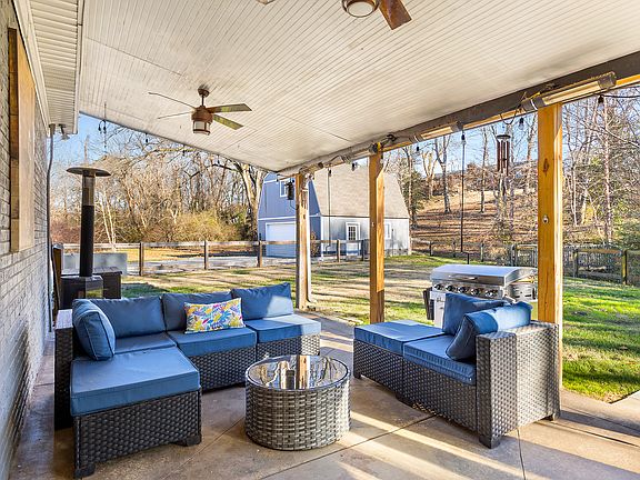 Unwind in the fenced-in private backyard with comfortable seating, grill, a fire pit, hot tub, deck, covered patio area and peaceful surroundings.